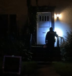 Police officer shines a flashlight on home
