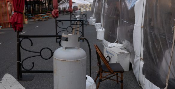 Propane heaters just up against the walls of a plastic tent.