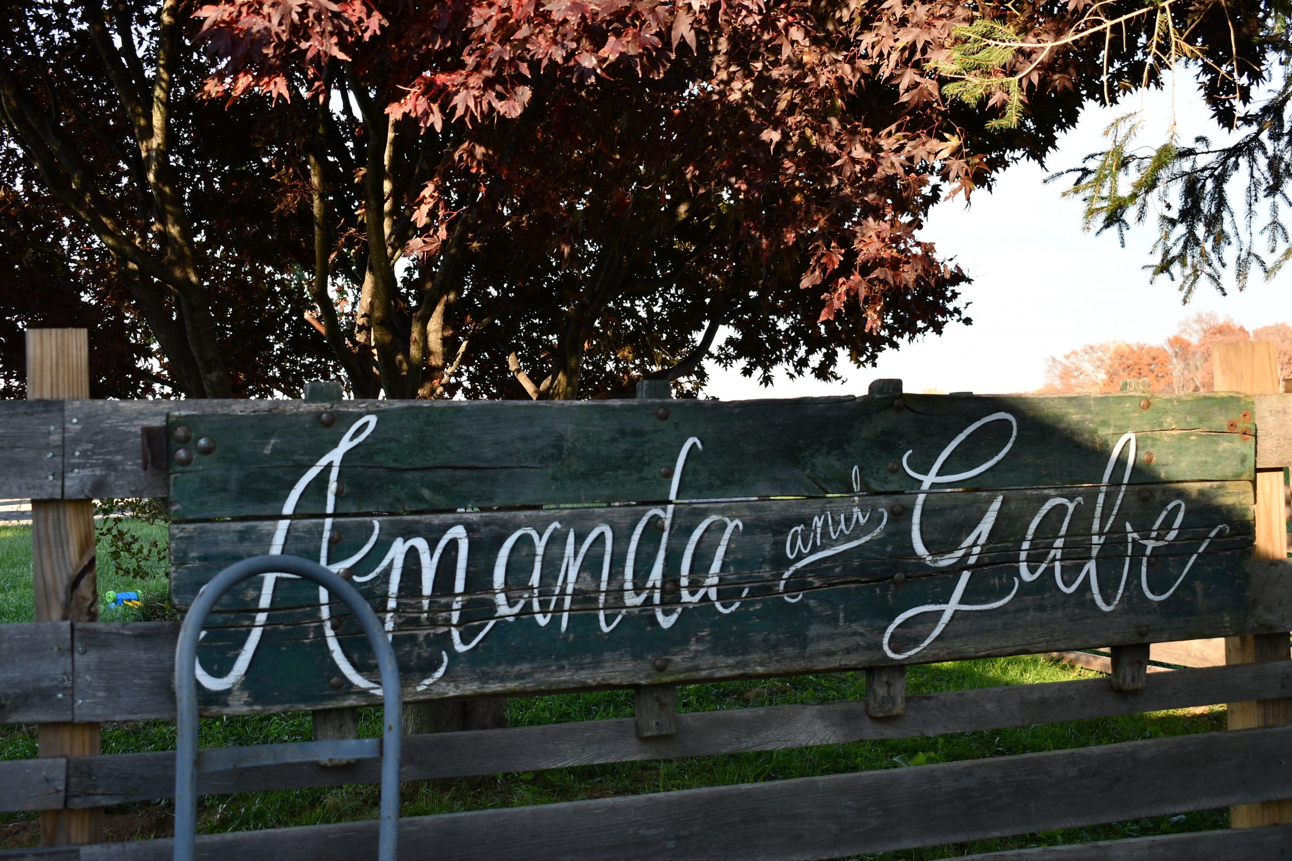 A photo of a hand-painted sign with white letters saying "Amanda and Gabe."