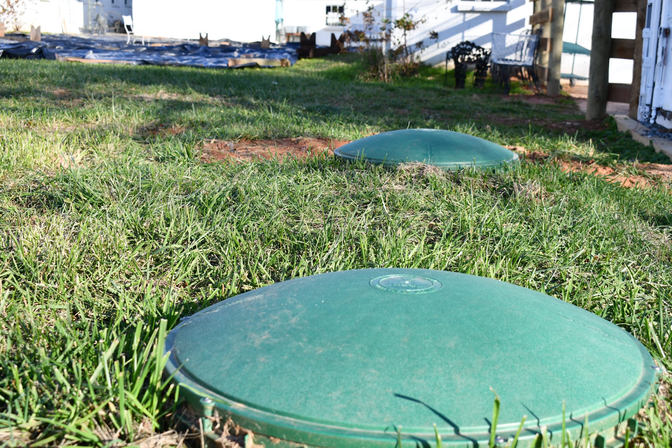 A photo of green barrels laid in-ground amid grass.
