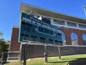 A scoreboard on the football field reads "Home of the Jackson-Reed Tigers"