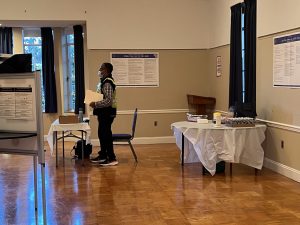 An election worker waits behind a table to help voters.