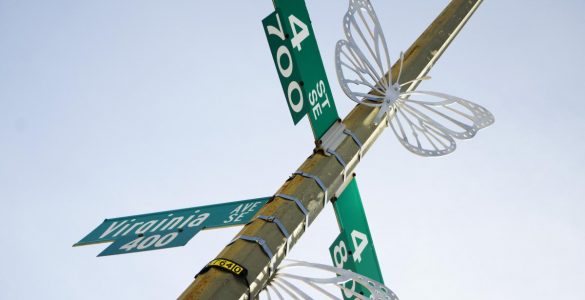 Two silver butterfly sculptures installed on the street sign on the corner of 4th Street and Virginia Avenue