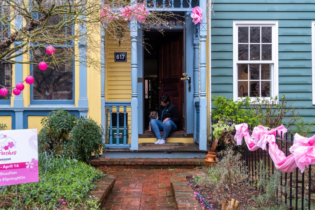 Karen Hopper sitting with a dog on a decorated porch during the National Cherry Blossom Festival in Washington, D.C.