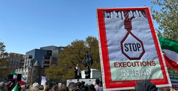 A demonstrator holds a sign that says "STOP executions in Iran".