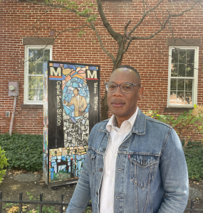 Curator Jarvis DuBois in front of Jabari Jefferson's sculpture featuring images of his family members and different Metro stops.