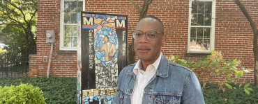 Curator Jarvis DuBois in front of Jabari Jefferson's sculpture featuring images of his family members and different Metro stops.