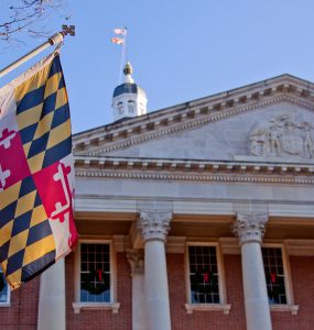 A close up view of the Maryland Statehouse with a state flag in the foreground The Maryland Statehouse with a state flag in the foreground. (Courtesy Glynnis Jones / Adobe Stock)