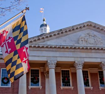A close up view of the Maryland Statehouse with a state flag in the foreground The Maryland Statehouse with a state flag in the foreground. (Courtesy Glynnis Jones / Adobe Stock)