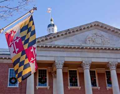 A close up view of the Maryland Statehouse with a state flag in the foreground The Maryland Statehouse with a state flag in the foreground. (Courtesy Glynnis Jones / Adobe Stock)