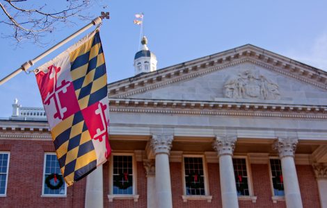 A close up view of the Maryland Statehouse with a state flag in the foreground The Maryland Statehouse with a state flag in the foreground. (Courtesy Glynnis Jones / Adobe Stock)