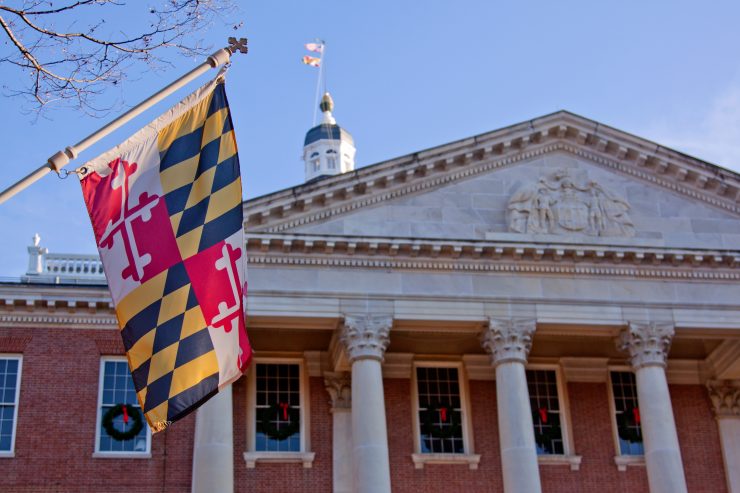 A close up view of the Maryland Statehouse with a state flag in the foreground The Maryland Statehouse with a state flag in the foreground. (Courtesy Glynnis Jones / Adobe Stock)