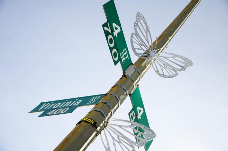 Two silver butterfly sculptures installed on the street sign on the corner of 4th Street and Virginia Avenue