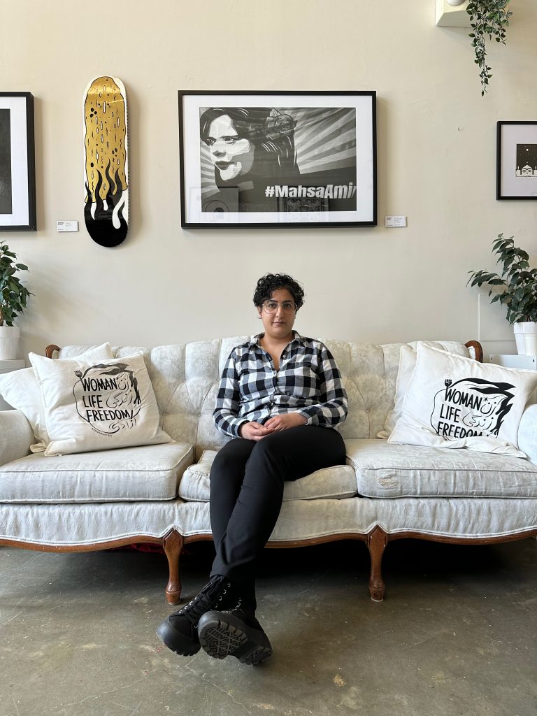 Mina Jafari sits on a white couch in her art studio.