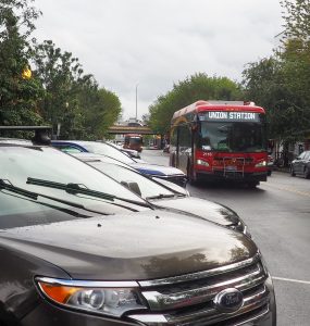 A bus drives past cars parked at an angle