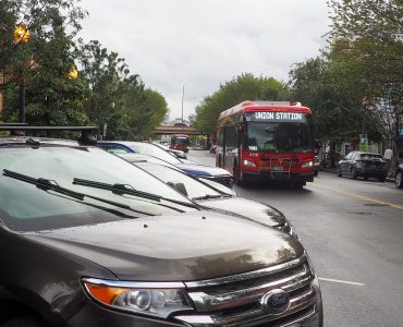 A bus drives past cars parked at an angle