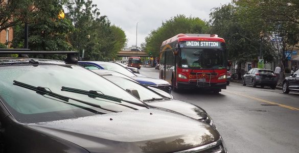 A bus drives past cars parked at an angle