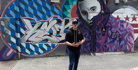 Cory Stowers standing in front of graffiti on a wall