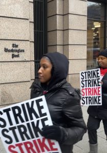 Two picketers hold "STRIKE" posters.