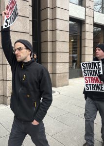 Two picketers hold "STRIKE" signs
