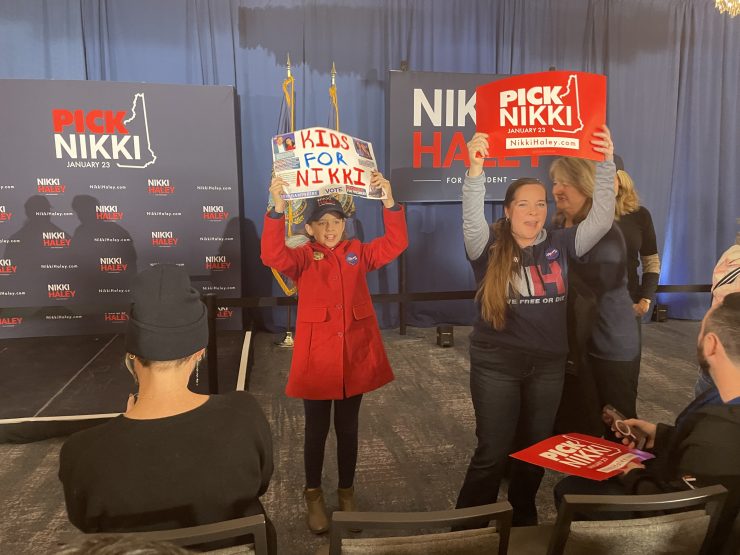 Potential voters in New Hampshire hold up political signs.