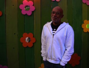 Vernon Wall poses in front of a wall with flowers on it.