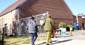 Two women hold hands while walking toward a polling place.