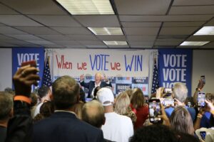 Minnesota Gov. Tim Walz speaks to a group of voters in front of a sign that says "when we vote we win.'