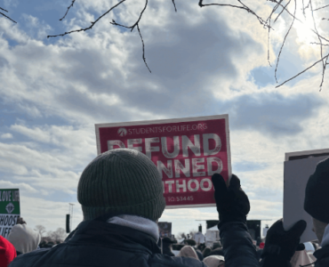 Protestor holding a defund planned parenthood sign at a DC rally