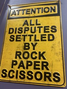 a sign that says "All disputes settled by rock, paper, scissors