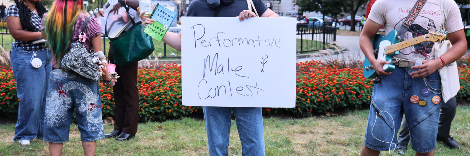 Nick Ransom, winner of the performative male contest, stands victorious while holding the sign for the competition. (Kelly Doyle)