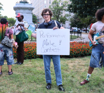 Nick Ransom, winner of the performative male contest, stands victorious while holding the sign for the competition. (Kelly Doyle)