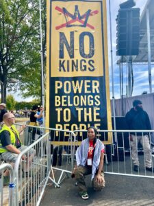 Imani Bashir poses in front of a D.C. ‘No Kings' rally sign (Courtesy of Imani Bashir)
