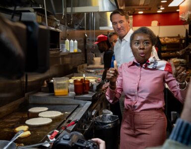 Winsome Earle-Sears, the Republican lieutenant governor of Virginia who is running for the top job, flips pancakes at Shorty's Diner in Richmond with a little help from her boss,Gov. Glenn Youngkin, on Monday. Voters will elect their first female governor on Tuesday. Photo by Ben Ackman