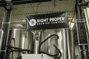 A Right Proper Brewing Company banner hangs above the production facility containment vats. (Terrance Williams)