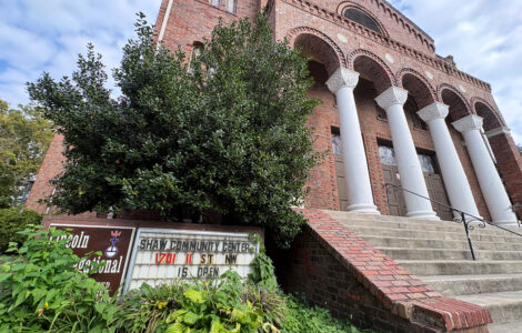 Looking up at the historic Lincoln Temple, an overgrown sign reads "Lincoln Congregational Temple United Church of Christ" and "Shaw Community Center 1701 11 St NW is open."