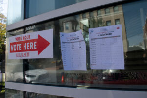 A sign reading "vote here" in three languages and two pages