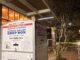 A white, steel box with blue and red lettering has a sign that reads "District of Columbia," "Board of Elections," and "Official Ballot Drop Box," each on individual lines. Arrows point to where ballots can be dropped into the box.